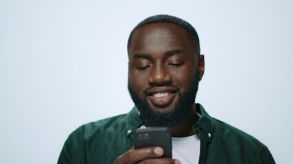 Portrait of smiling african american man using smartphone on grey background.