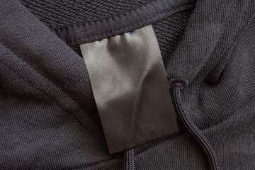 Blank black laundry care clothes label on black fabric texture background