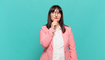 young business woman feeling thoughtful, wondering or imagining ideas, daydreaming and looking up...
