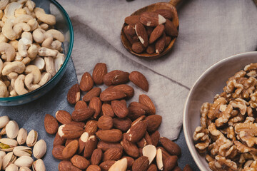 mixed nuts in ceramic bowls, wooden spoon. Almonds, walnuts, cashew nuts, pistachio nuts