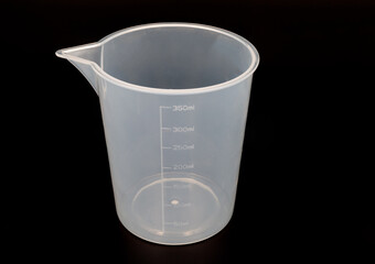 plastic measuring cup on black background close up