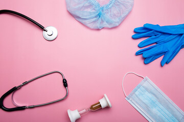 Disposable medical cap, protective gloves and face mask on pink background