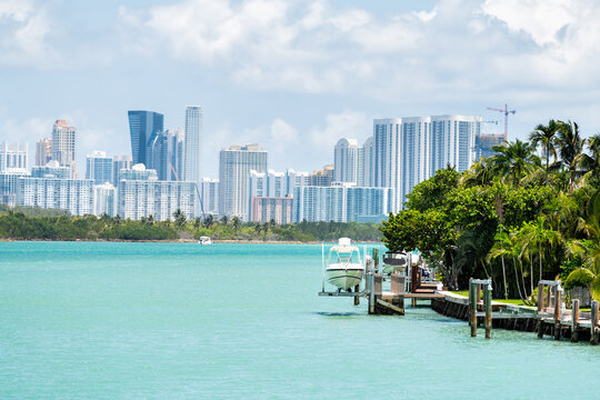 Bal Harbour, Miami Florida house dock with boat by light green turquoise ocean Biscayne Bay Intracoastal water and cityscape Sunny Isles Beach cityscape