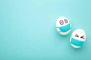 White Easter eggs in protective medical mask on blue background. Easter on quarantine concept with place for text. Stop VIRUS COVID-19. Copy space. Egg in mask.