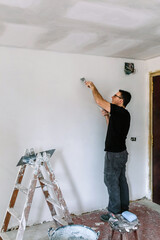 Male bricklayer repairing the wall with a spatula
