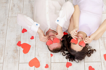 valentine's day, a couple in love lies among the hearts on the floor with their eyes closed with hearts