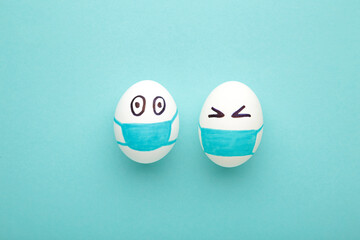 White Easter eggs in protective medical mask on blue background. Easter on quarantine concept with place for text. Stop VIRUS COVID-19. Copy space. Egg in mask.