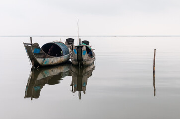 Two sampan shrimp fishing boats with a reflection in a lake between Hue and Hoi An, Central Vietnam.