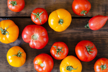 Red and yellow tomatoes on wooden background. Top view.