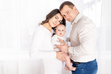 happy family mother and father hold a newborn baby at home, the concept of happy loving family, lifestyle