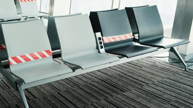 Social distance at airport. Prohibiting ribbons on chairs for waiting departure at terminate. Empty seats in waiting room of terminal aircraft. New rules, norms for travel due pandemic coronavirus