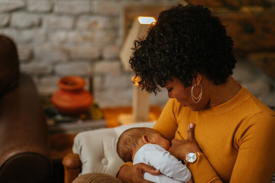 Mom breastfeeds newborn baby at home