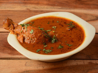 Chicken masala made of indian spices served in a bowl over a wooden rustic background. selective focus