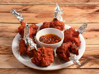 Chicken lollipop is Indian Chinese appetizer served over a wooden rustic background. selective focus
