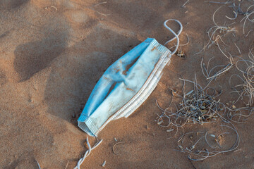 COVID-19 coronavirus blue disponable mask garbage in the sand for global pandemic environmental...
