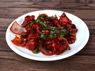 Chilli Chicken is an Indian Chinese starter served over a wooden rustic background. selective focus