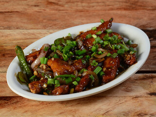 Chilli Chicken is an Indian Chinese starter served over a wooden rustic background. selective focus