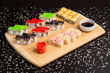 Big sushi set on light wooden dish isolated on black background