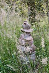 A tower of stones in the grass on a tourist path in the forest.