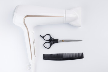 Hairdryer for drying hair scissors and comb on a white background. Top view.