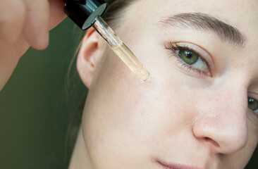 Portrait of a woman applying liquid from a glass bottle, skin texture. Apply a moisturizing tea...