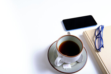 Book, glasses, smartphone and cup of tea on a white background