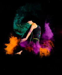 Obraz na płótnie Canvas A young woman makes a high jump with explosion of dry colorful holi powder. Holi festival india