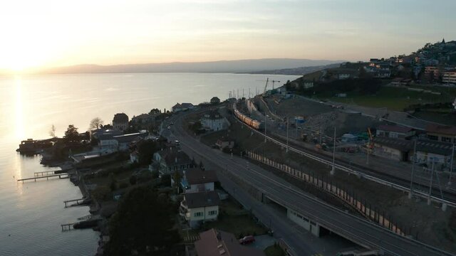 Aerial of train driving past highway near beautiful lake