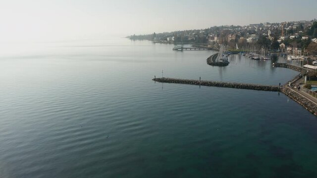 Flying over woman standing on end of quay in beautiful coastal city