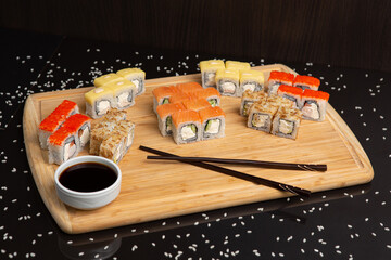 Fototapeta na wymiar Big sushi set on light wooden dish isolated on black background