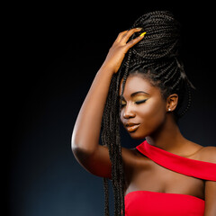 African woman holding braids with eyes closed.