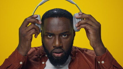Portrait of surprised african guy listening music on headphones in studio.