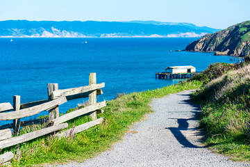 Unpaved hiking trail on cliff edge leading to lifeboat station at at Point Reyes Headlands. Scenic...
