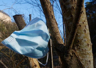 corona medizinische maske mundschutz, hängend auf einem baum in der Natur