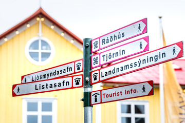 Reykjavik, Iceland street road in downtown center and sign by yellow vibrant colorful house building restaurant exterior for directions to landmarks