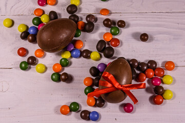 Chocolate easter eggs and multicolored candies on wooden table. Top view