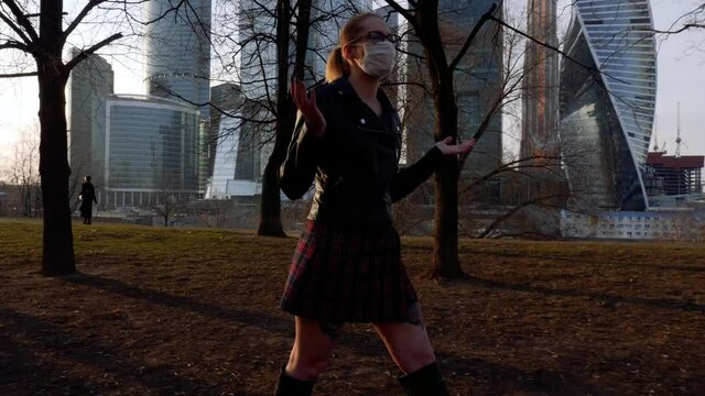 Lady in scott skirt, leather jacket and medical mask walking through the spring city with skyscrapers