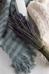 Bouquet of lavender tied with a golden and black ribbon over a warm blanket and a beige loungewear.