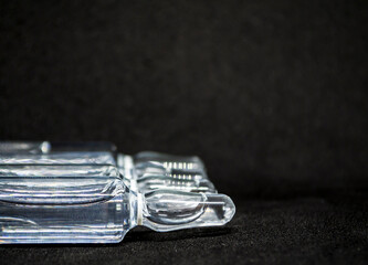 Glass medical ampoule vial for injection. Medicine is liquid sodium chloride with of aqueous solution in ampulla. Close up. Bottles ampule multicolor on background color and water. Human plasma.