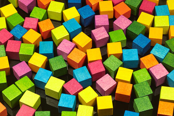 Bunte Holzwürfel liegen auf einer schwarzen Metallplatte.