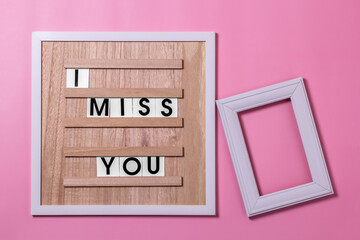 lettering on the quote board I miss you with a photo frame on a pink background.