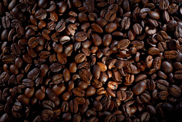 Coffee beans close up. Texture of brown coffee beans. Contrasting dramatic light as an artistic effect.