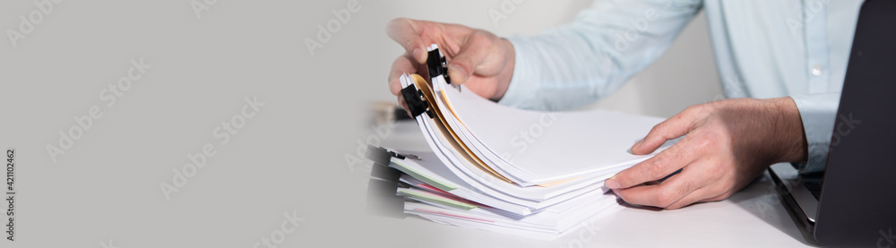 Poster man working computer and stack of documents
