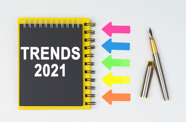 On a white background lies a pen, arrows and a notebook with the inscription - TRENDS 2021