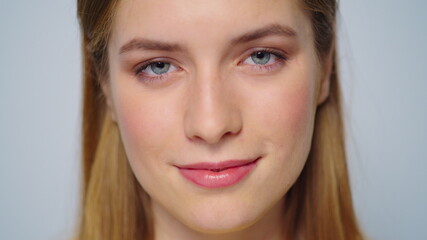 Obraz premium Closeup pretty girl face smiling at camera on grey background.