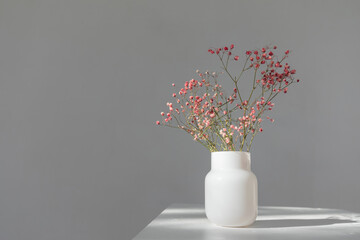 Minimalistic composition of dried pink flowers in cylindrical glass vase