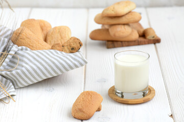 Freshly baked homemade crunchy cookies with glass of milk. A delicious treat for gourmets, sweet breakfast. Biscuits on a white wooden background