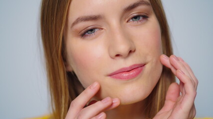 Fototapeta premium Closeup attractive smiling woman touching face with hands at camera indoors.