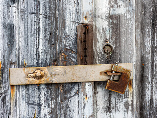 A dilapidated closed door with a rusty padlock