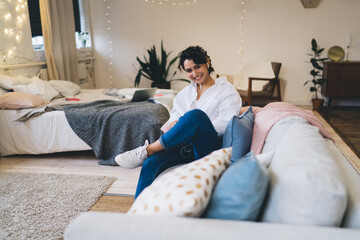 Happy woman sitting on cozy couch in bedroom